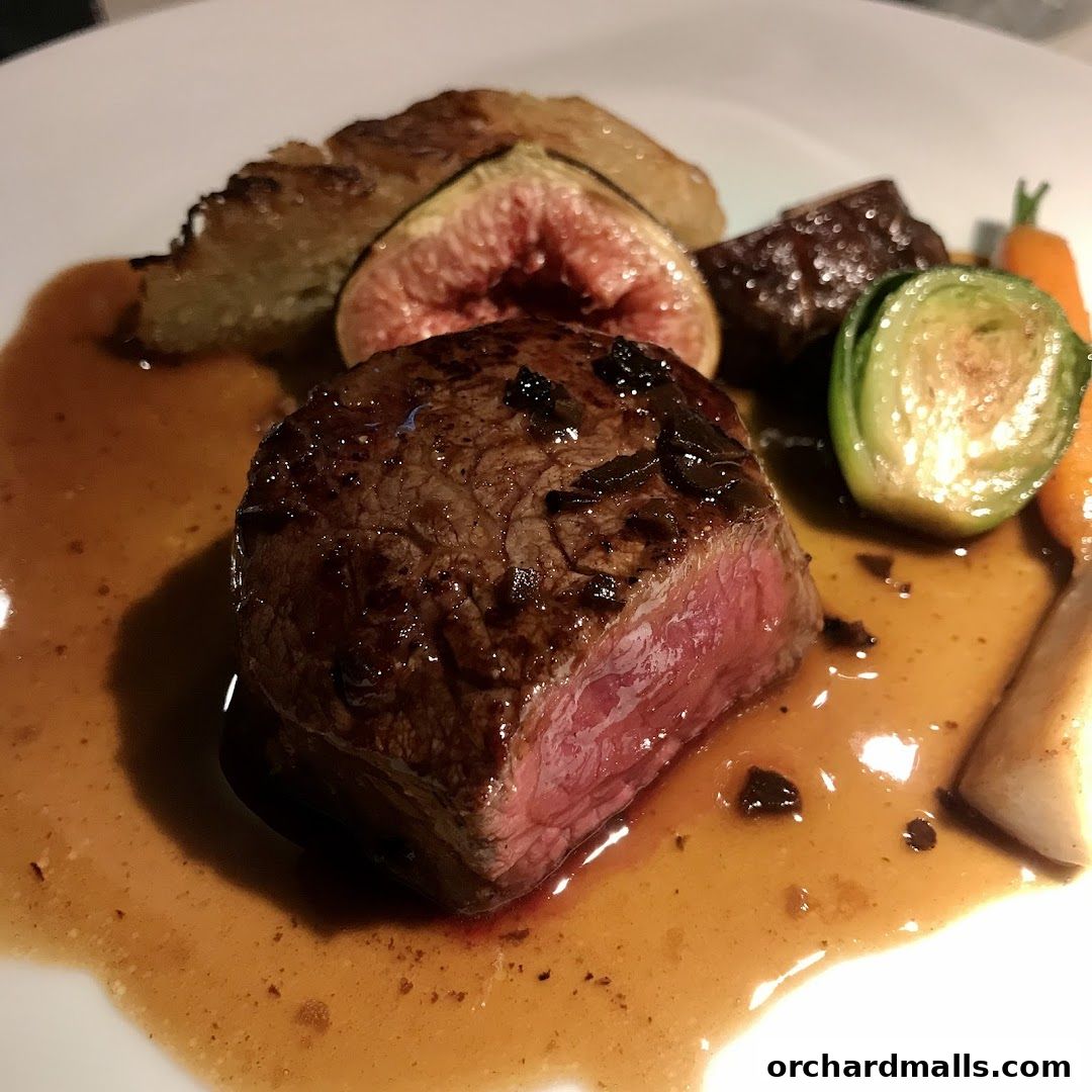 A perfectly cooked steak with fig, Brussels sprouts, carrots, and potatoes in a rich sauce.