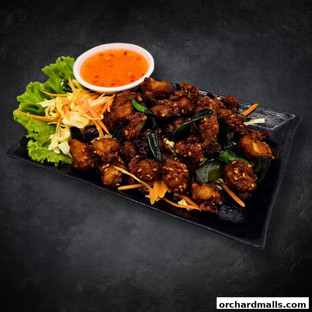 A plate of crispy Thai chicken bites with a side of sweet chili sauce and salad.