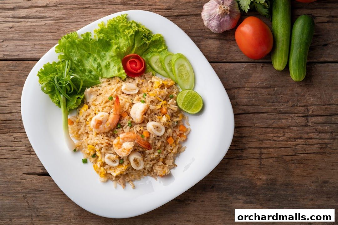 A plate of Thai fried rice with shrimp and squid, garnished with lettuce and lime.