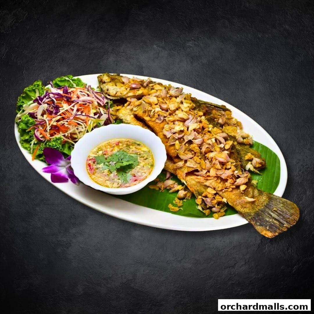 A whole fried fish topped with garlic, served with salad and dipping sauce.
