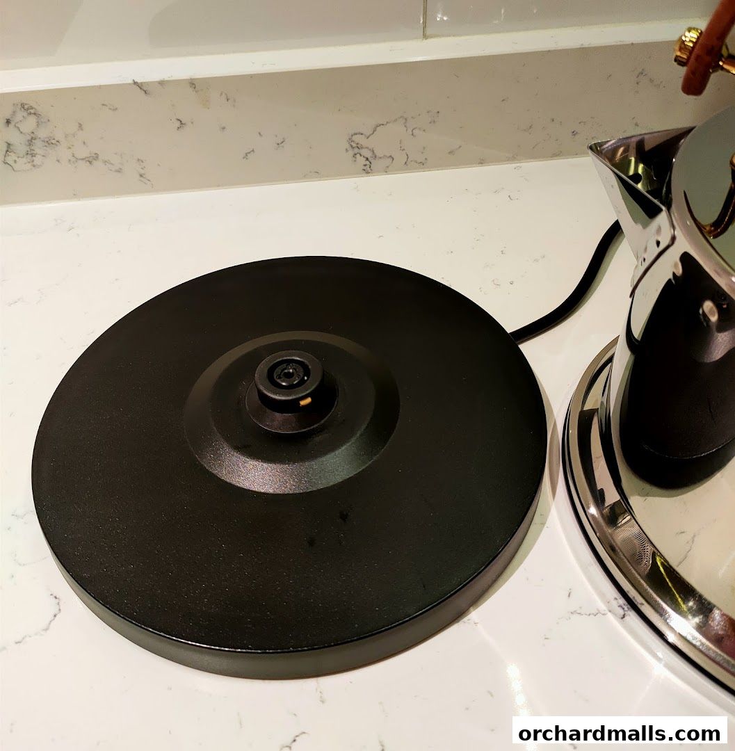 A close-up of a black electric kettle base and part of a stainless steel kettle.