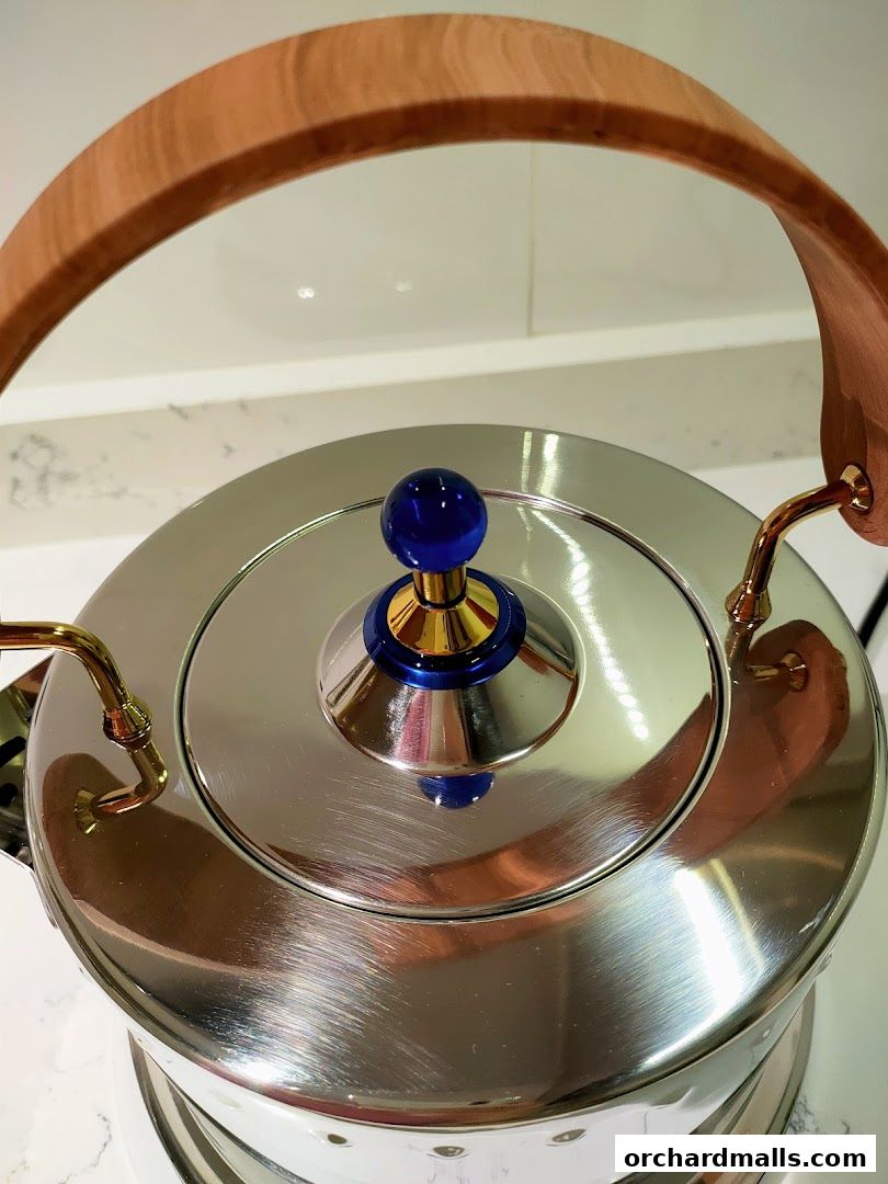 Close-up of a shiny stainless steel kettle with a wooden handle and blue knob.