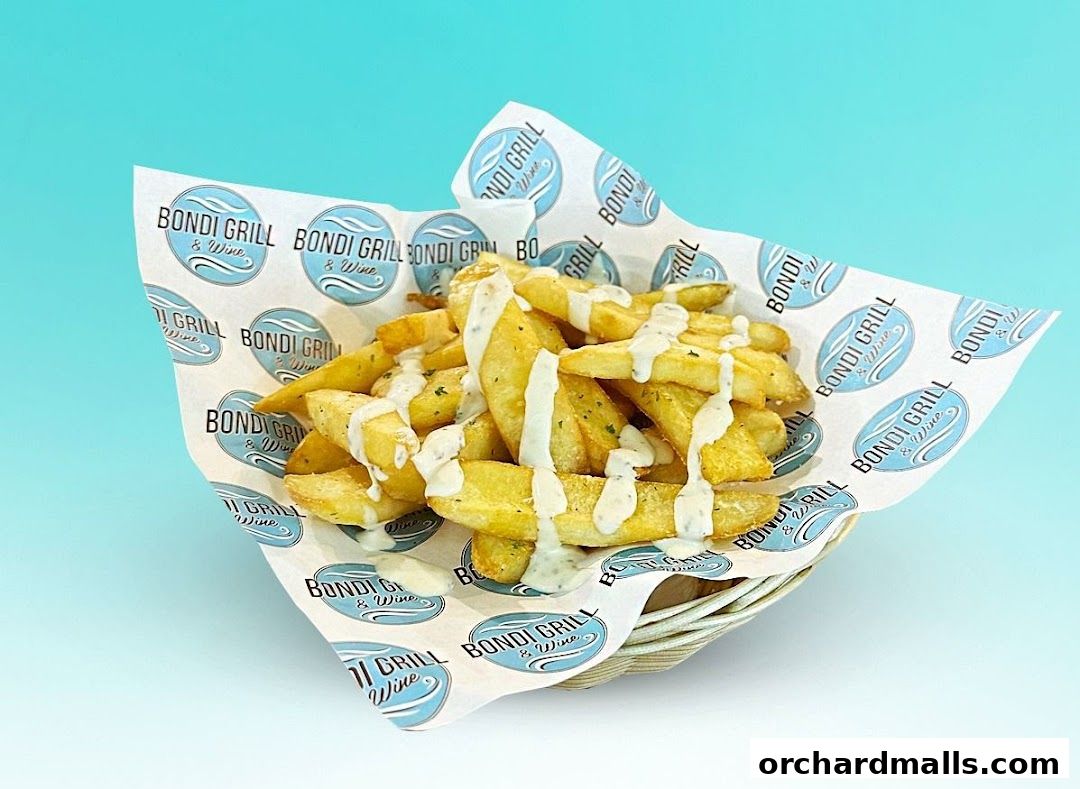A basket of golden fries drizzled with a creamy sauce, served on branded paper.