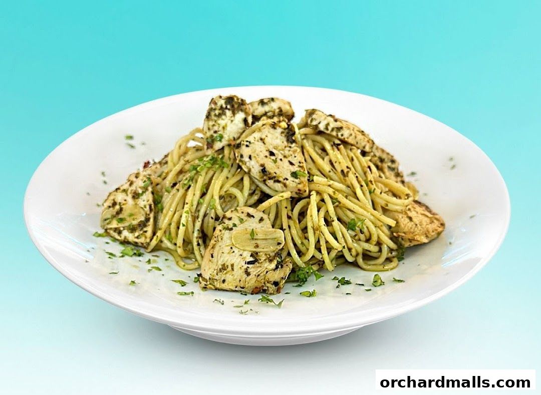 A white plate filled with spaghetti and grilled chicken pieces, garnished with parsley.