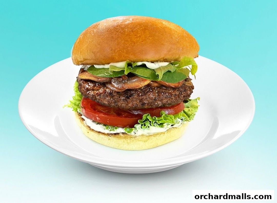 A juicy burger with mushrooms, tomato, lettuce, and sauce on a white plate.