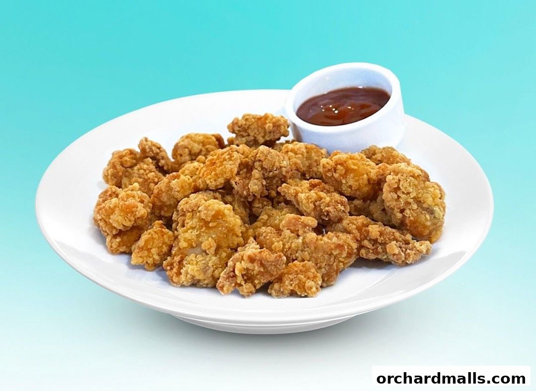 A plate of crispy fried chicken bites served with a side of dipping sauce.