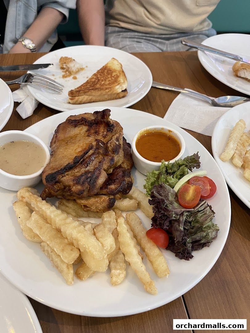 A grilled chicken steak with fries, salad, and dipping sauces on a plate.