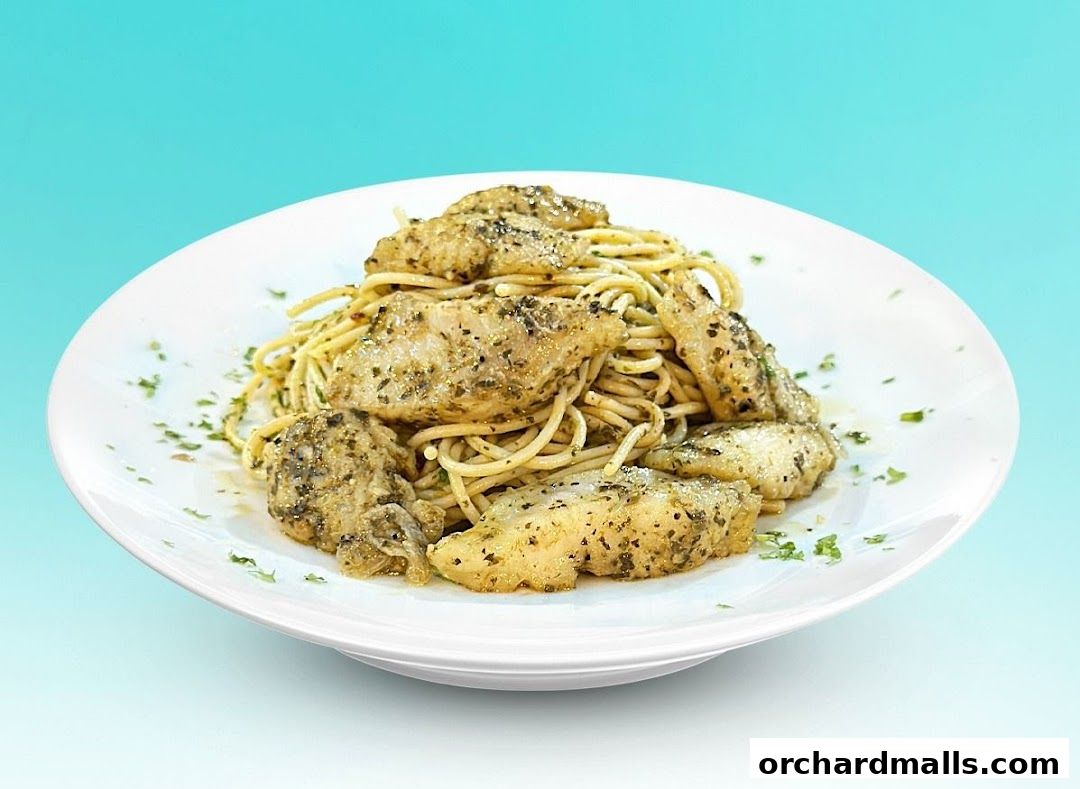 A white plate filled with spaghetti topped with seasoned grilled chicken pieces and parsley.