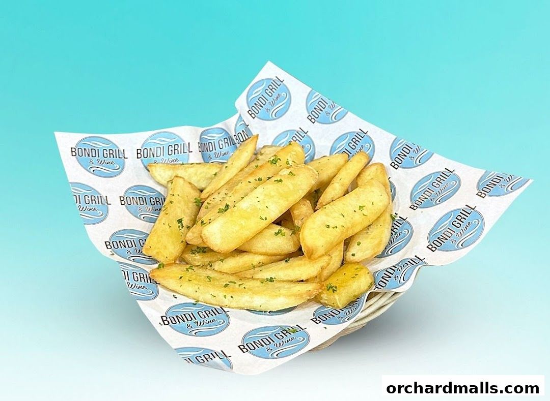 A basket of golden potato wedges seasoned with herbs, served on branded paper.