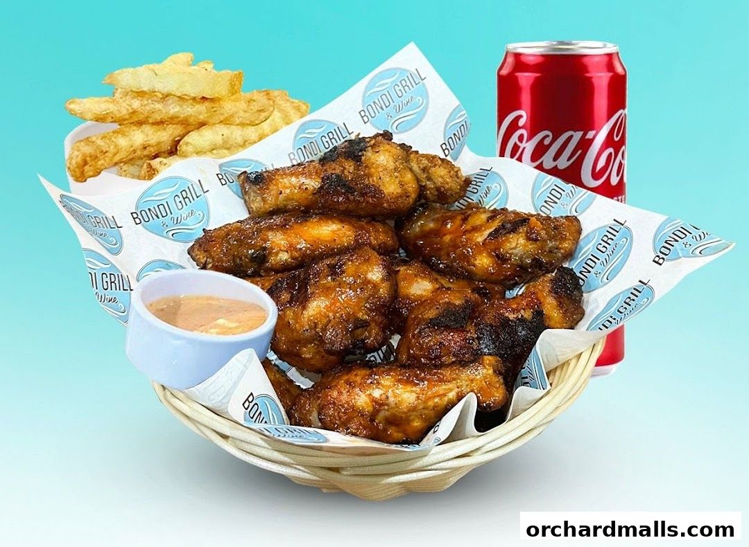 A basket of grilled chicken wings with fries and a can of Coca-Cola.