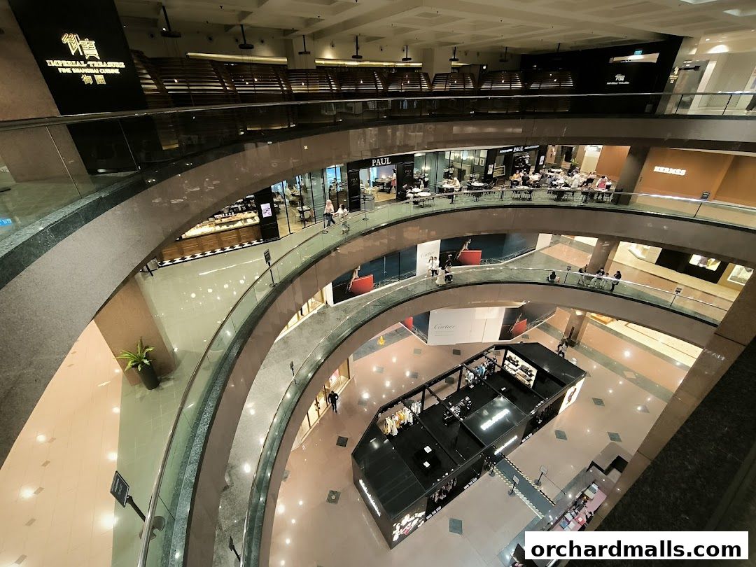 Interior view of a multi-level shopping mall with various luxury stores and a central display.
