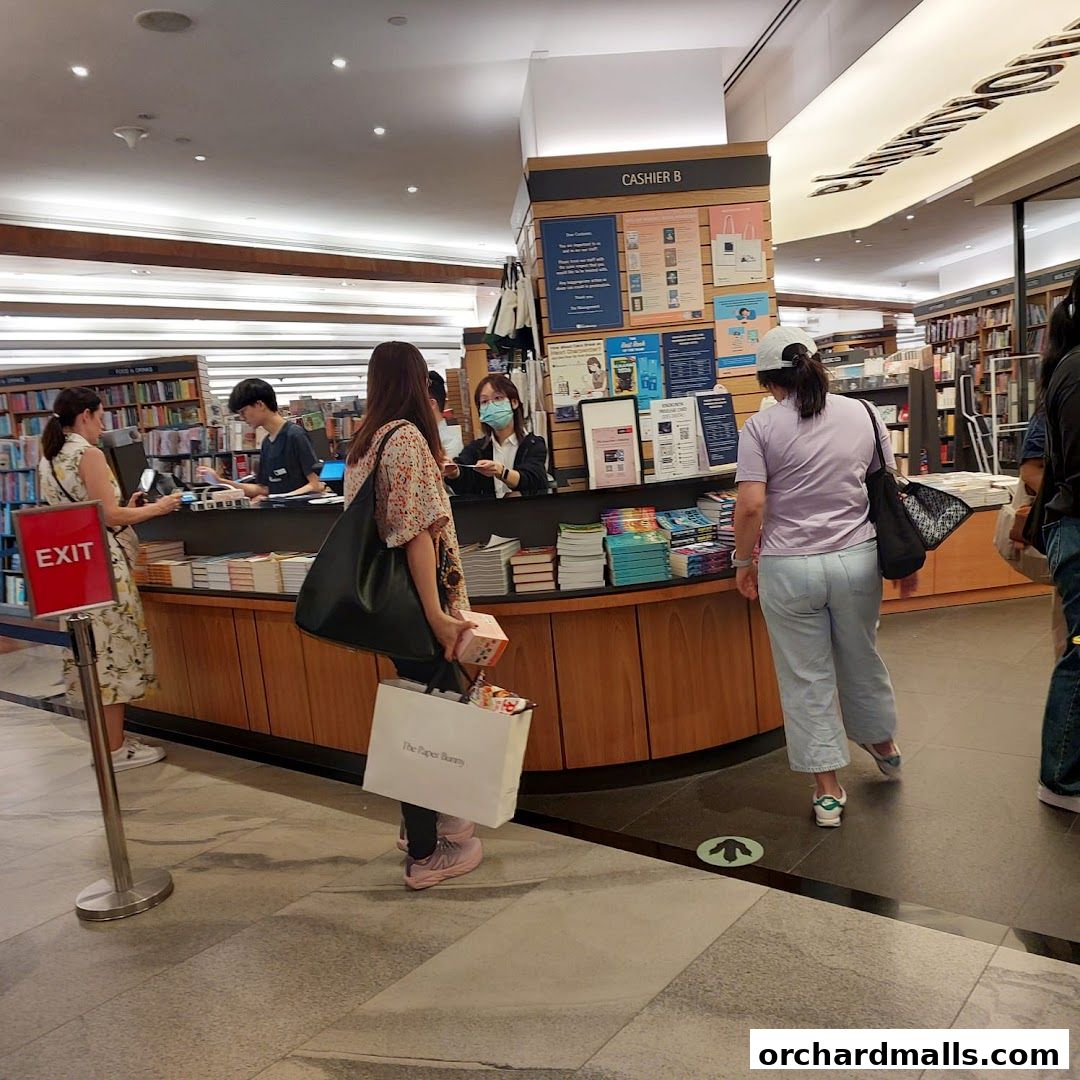 Customers at the cashier counter of a bookstore, with shelves of books in the background.