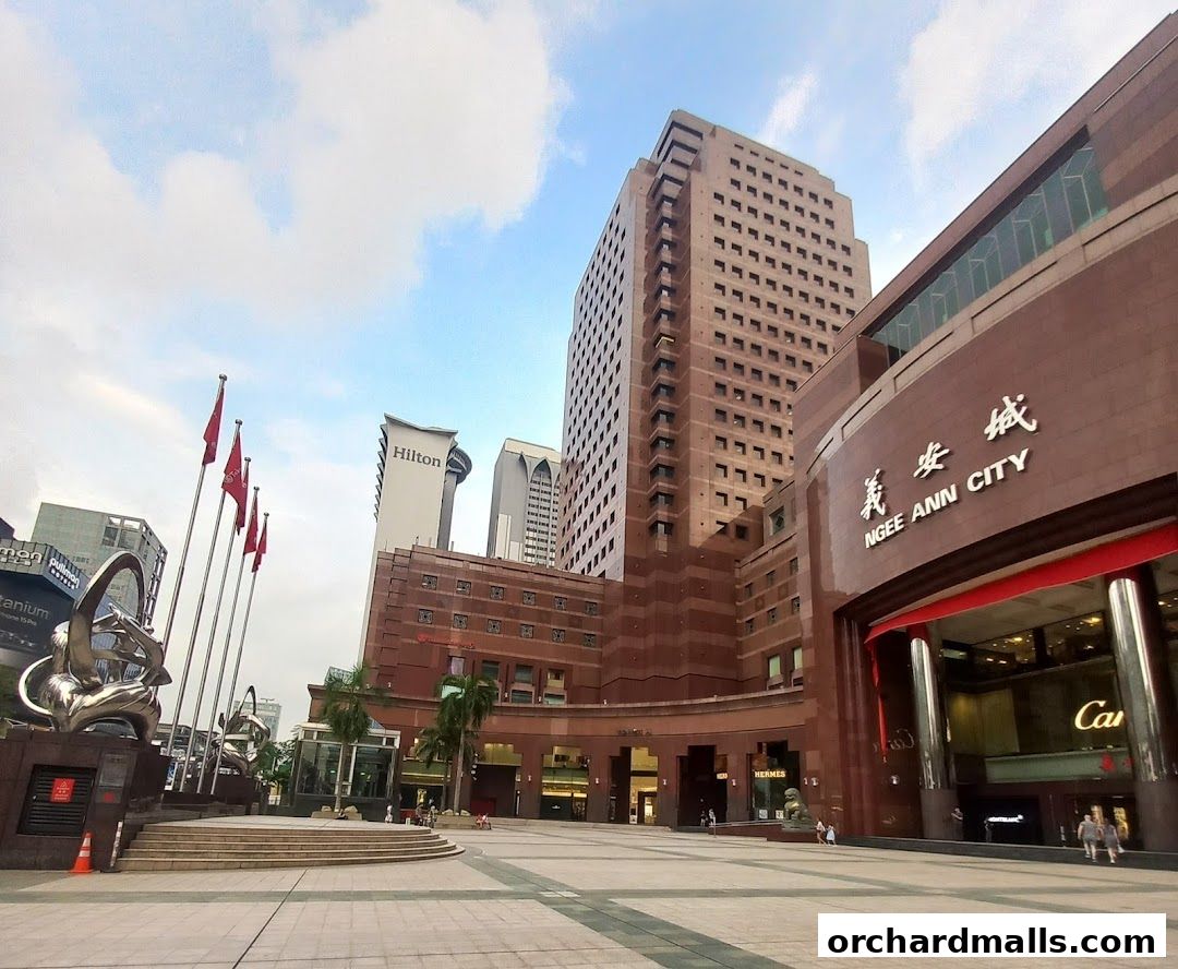 Exterior view of Ngee Ann City mall with surrounding buildings and sculptures.