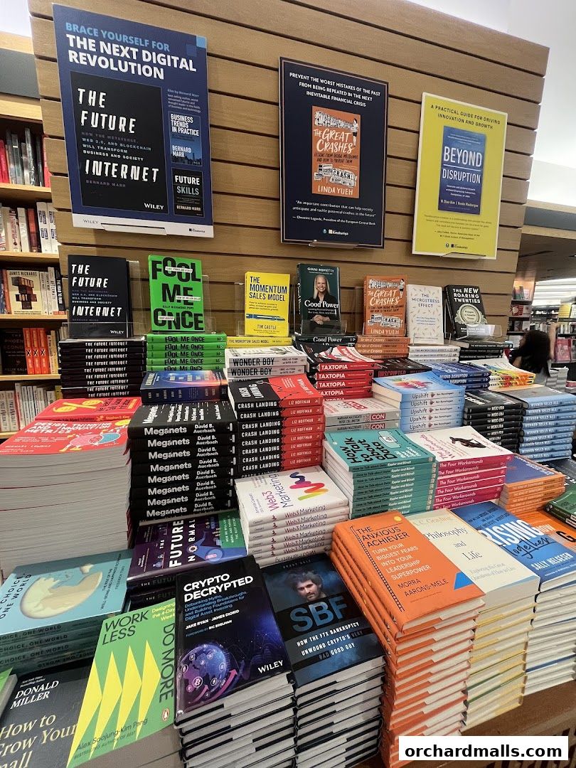 A display of business and finance books at Kinokuniya bookstore, featuring titles on digital revolution, financial crises, and innovation.