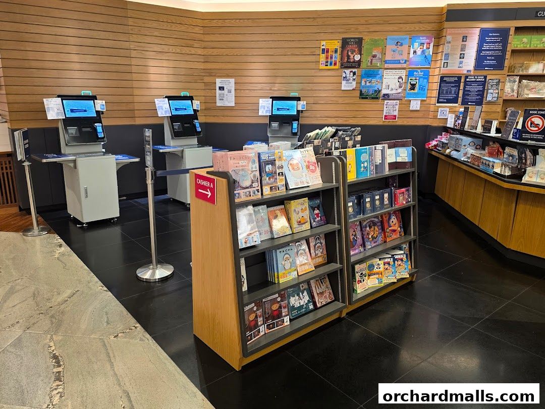 Interior view of a bookstore with self-checkout kiosks and shelves of books.