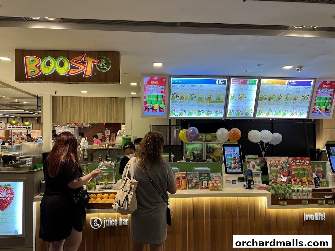 Customers ordering at a Boost Juice bar with colorful menus and promotional displays.