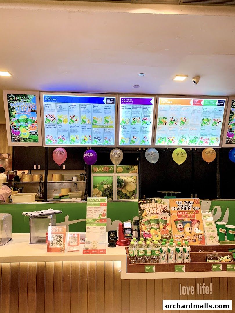 A Boost Juice counter with illuminated menus displaying popular drinks and add-ons.