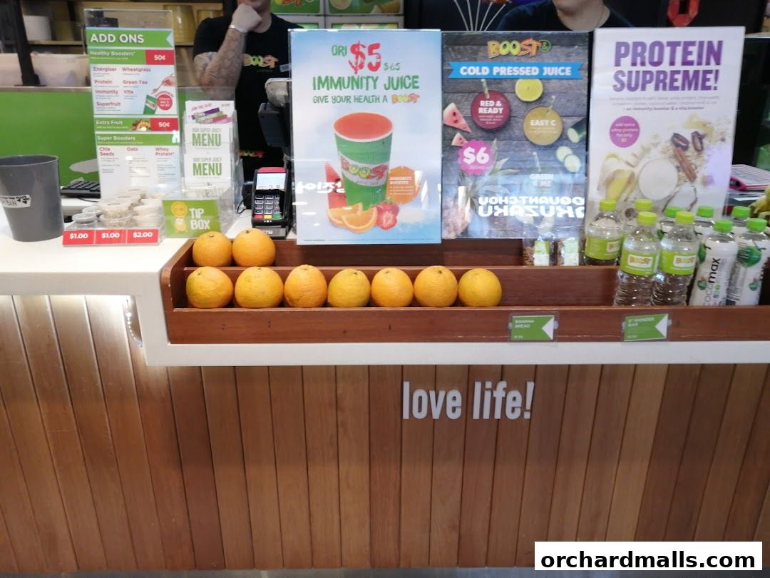 A Boost Juice counter displaying various juices, protein drinks, and fresh oranges.