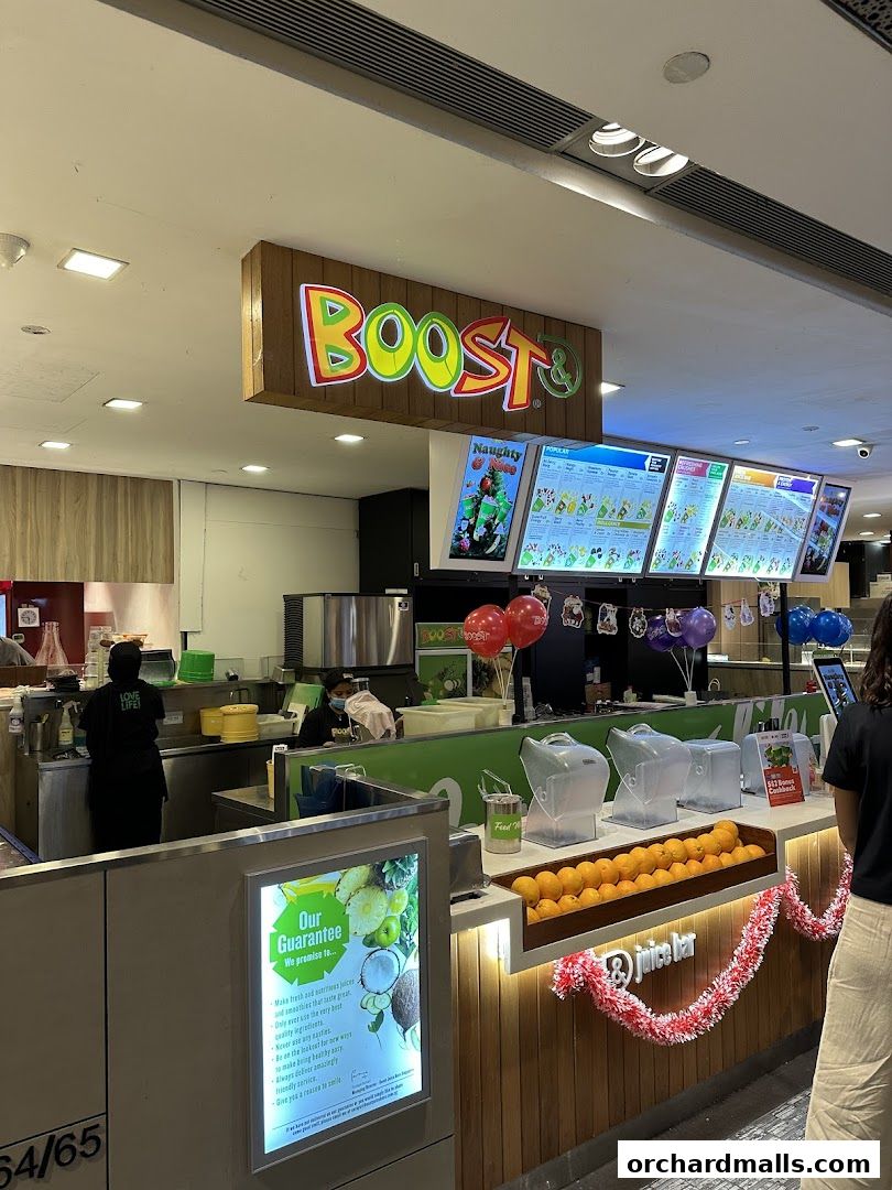 The Boost Juice shop front with a colorful sign, menu boards, and fresh fruit displayed.