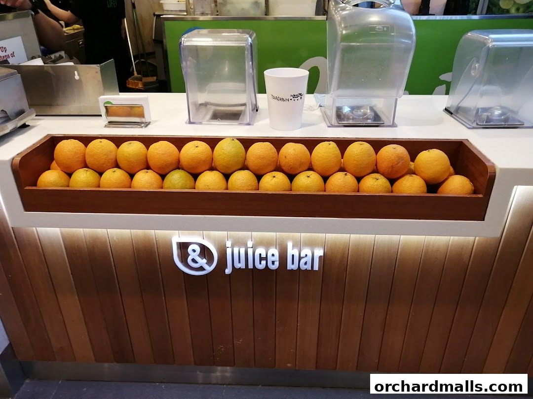 A juice bar counter displaying fresh oranges and the shop's logo.