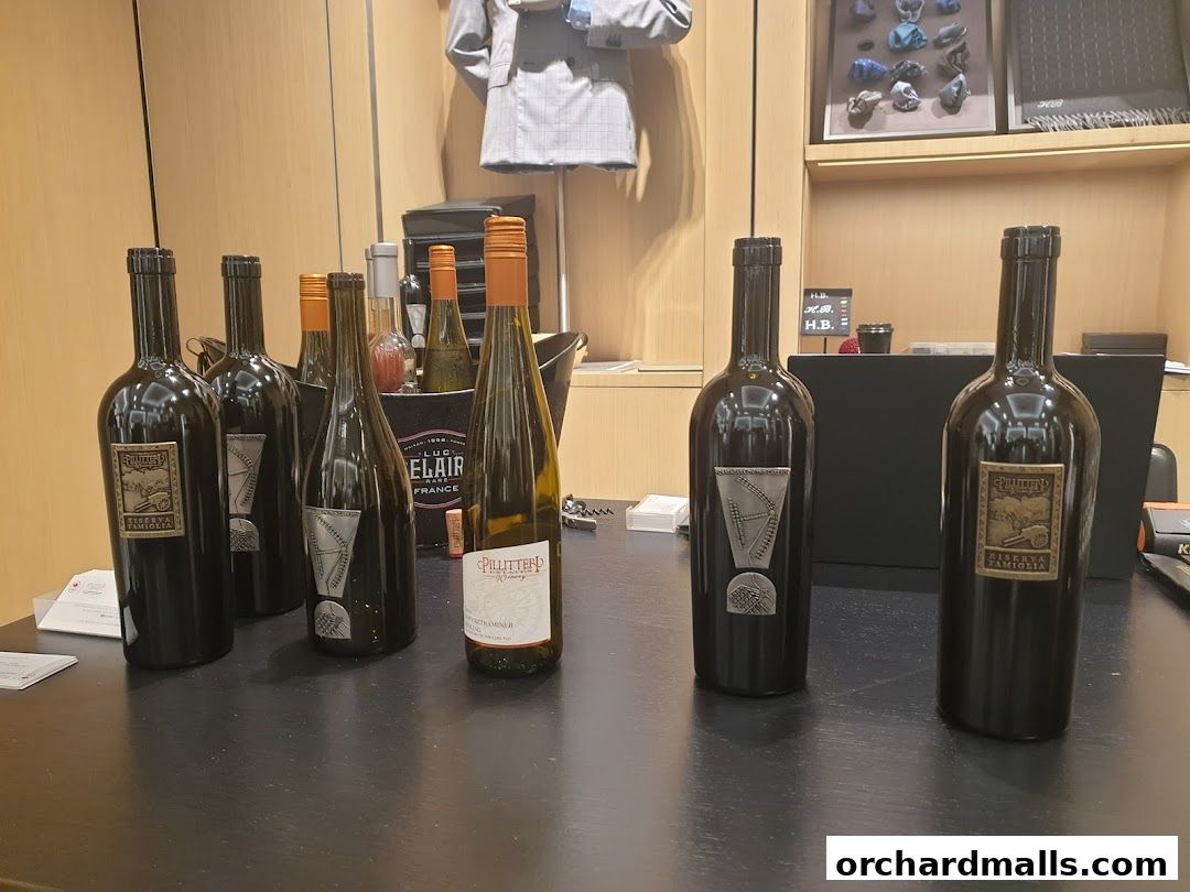 Several bottles of wine are displayed on a dark surface in front of a store.