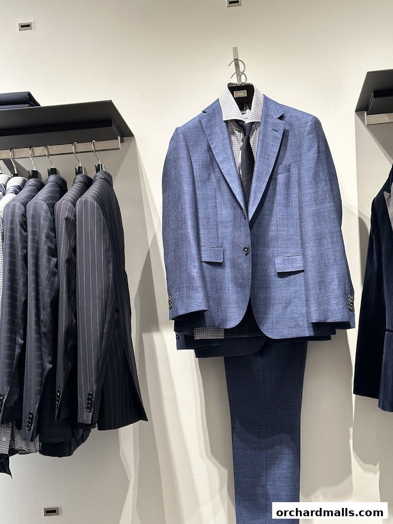 A display of men's suits and jackets hanging on a wall in a retail store.