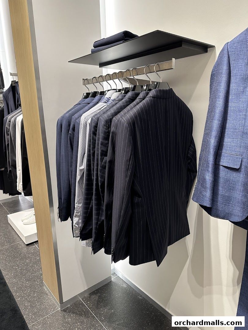 A row of men's suits and jackets displayed on hangers in a retail store.