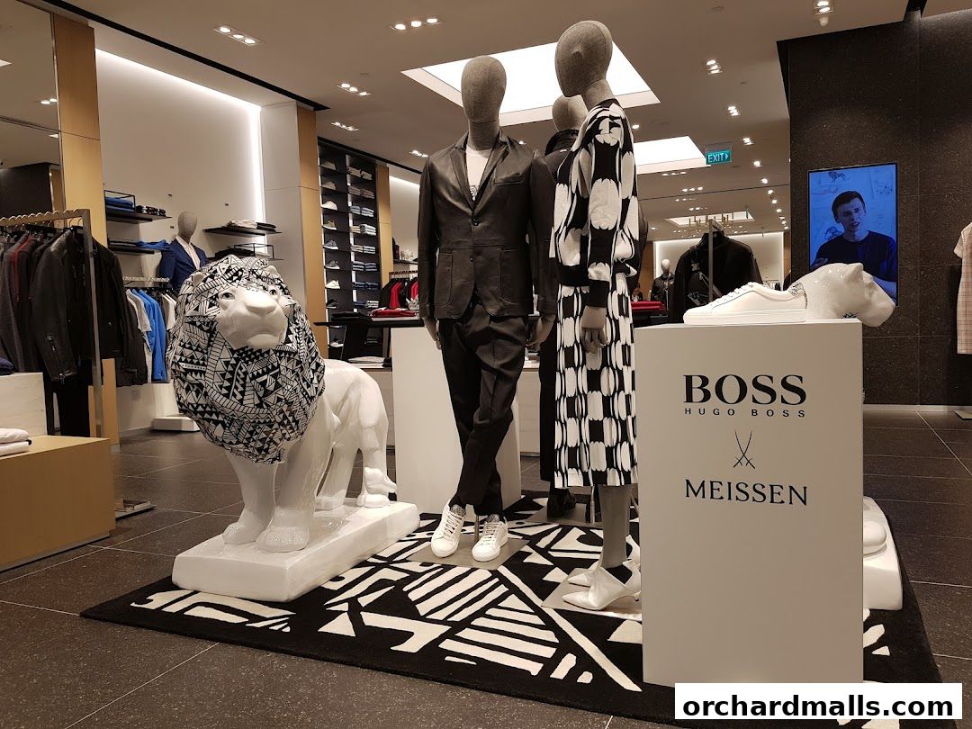 Mannequins display BOSS Hugo Boss fashion with a decorative lion statue inside the store.
