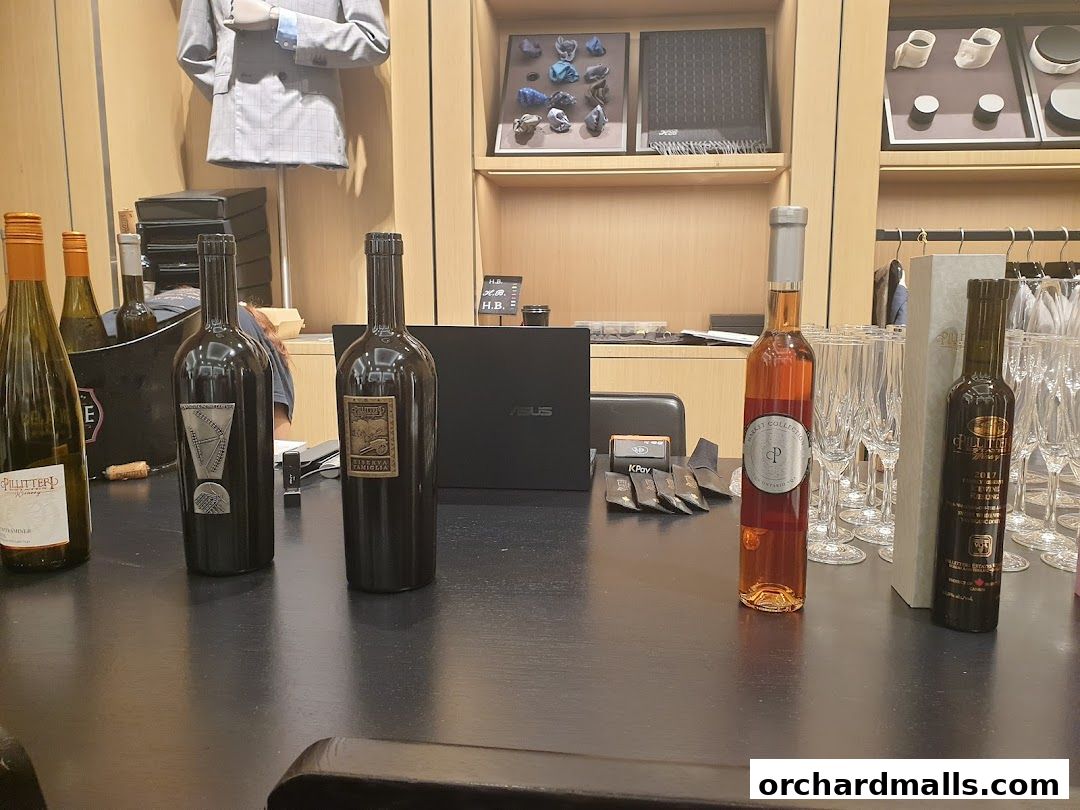 Bottles of wine and champagne glasses are displayed on a counter in a retail store.