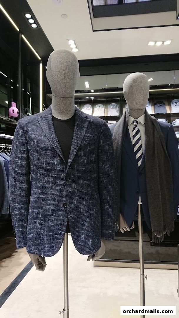 Mannequins display stylish blazers and suits in a well-lit retail store.