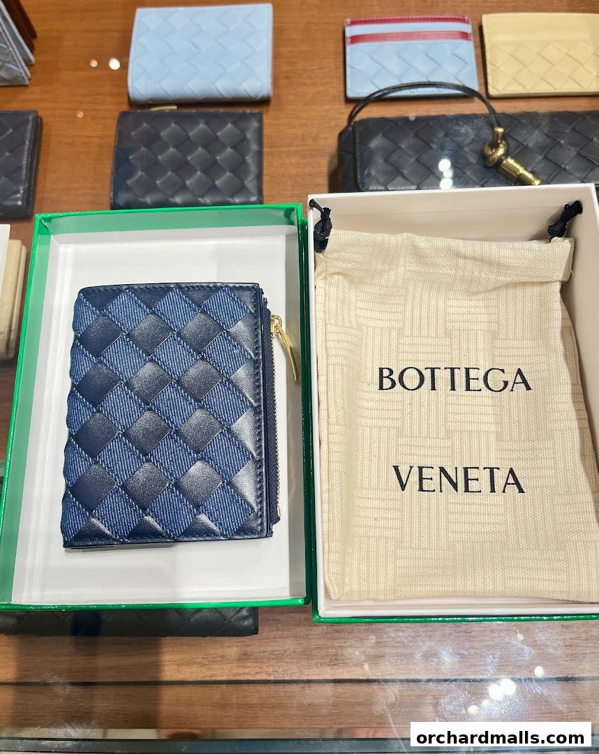 Bottega Veneta wallet and dust bag displayed in a retail setting.