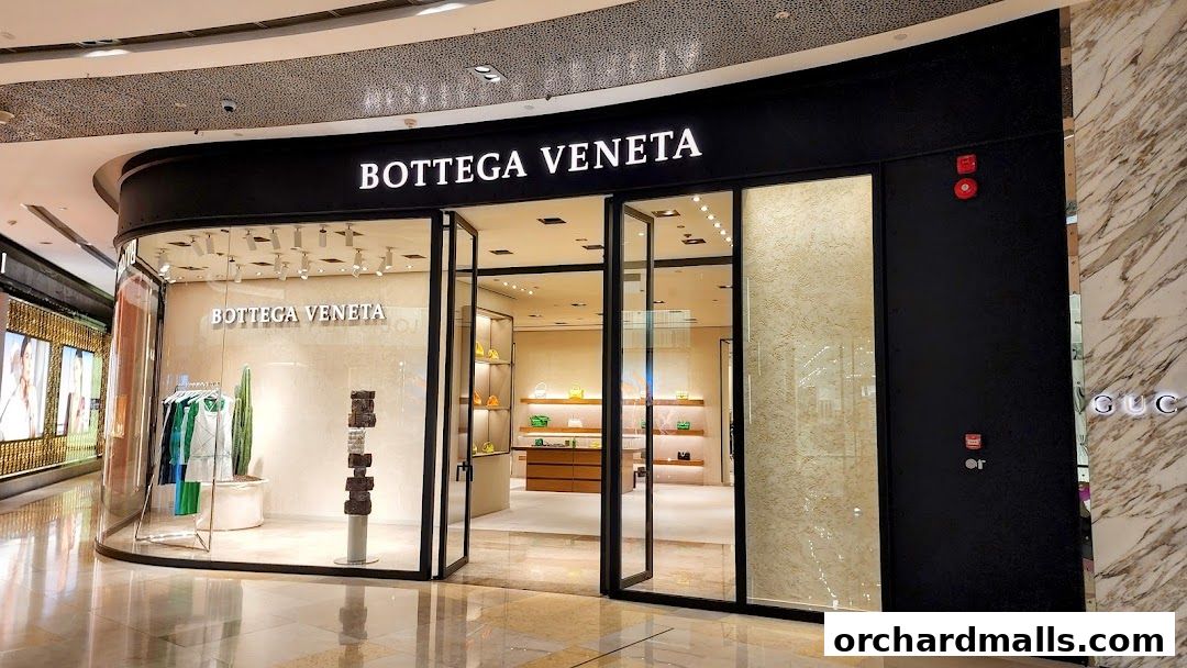 The elegant Bottega Veneta store entrance with display of luxury handbags and apparel.