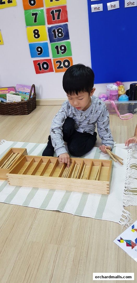 A young boy engages with a Montessori learning material on the floor.