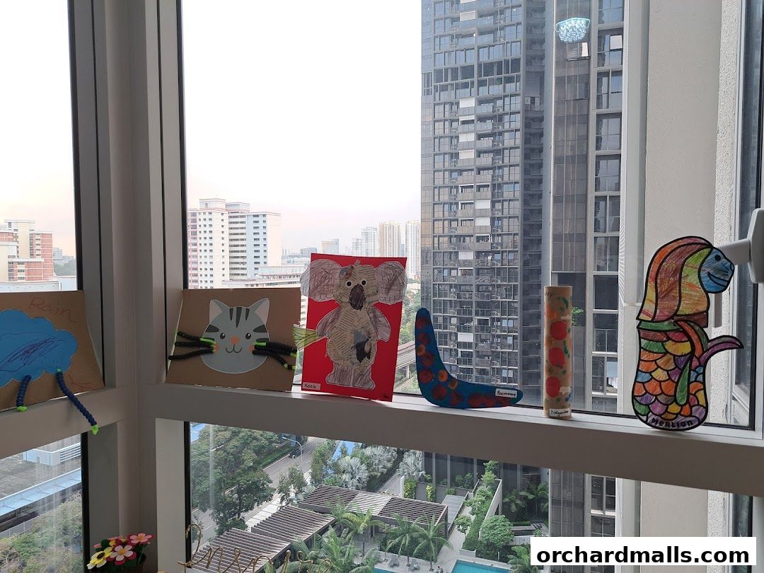Children's artwork displayed on a windowsill overlooking a city skyline.
