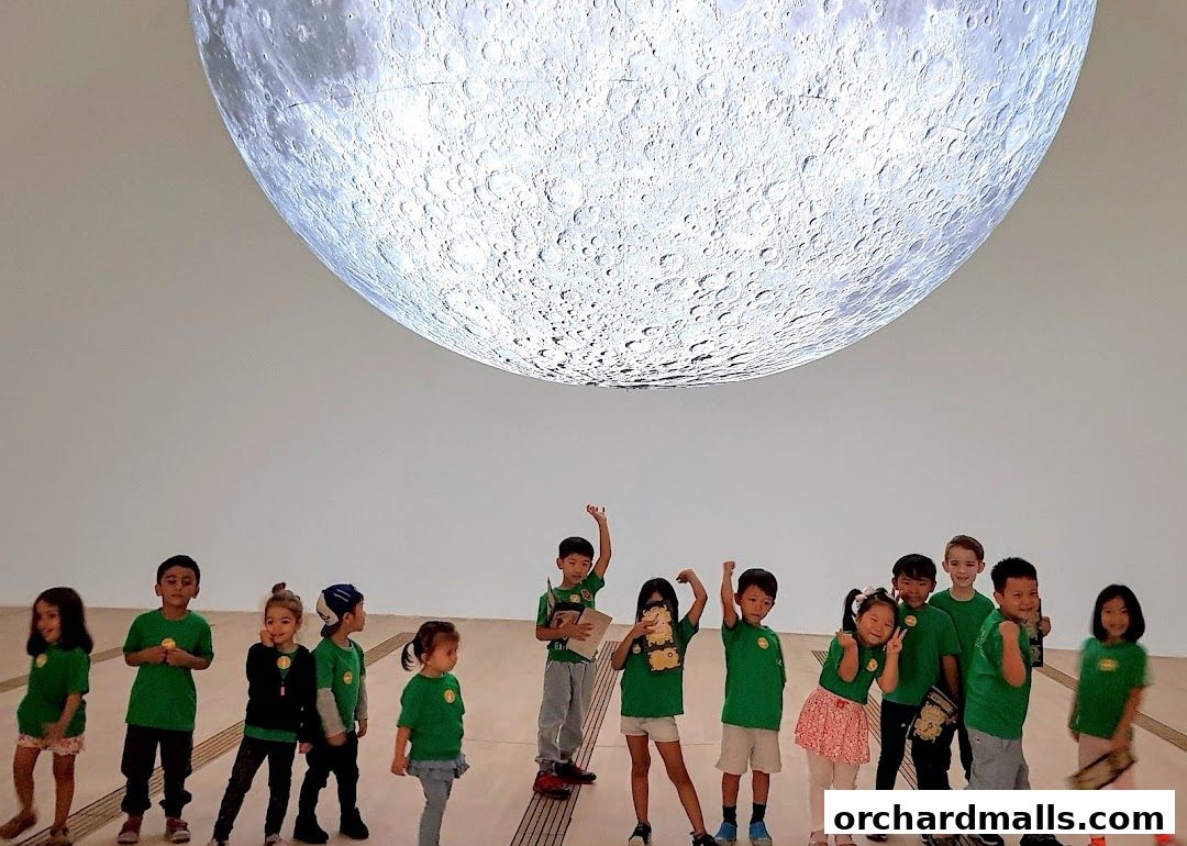 Children in green shirts pose under a large moon projection.
