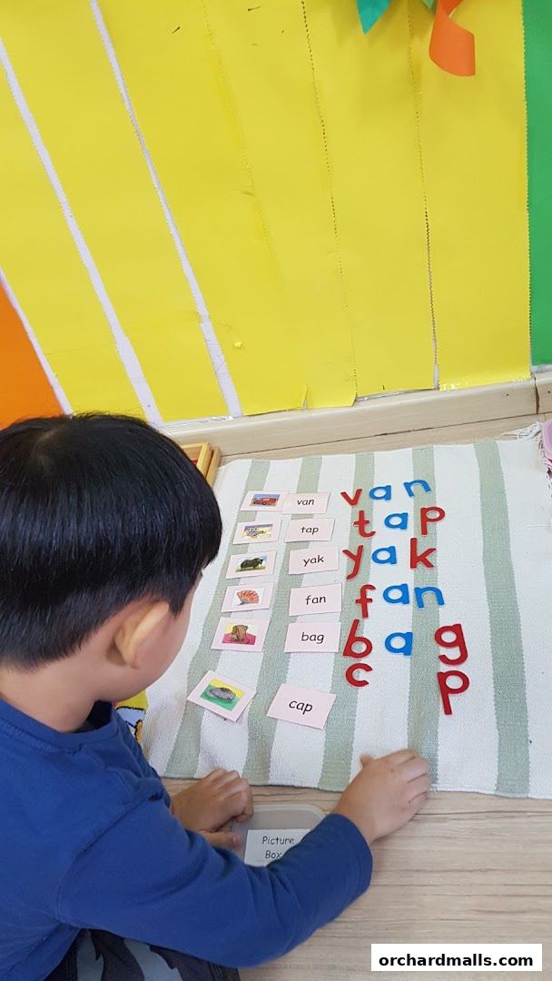 A child learns phonics with picture cards and letter tiles at Brainy Child Montessori.