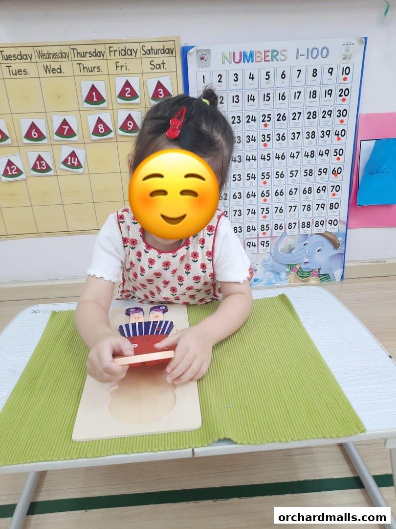A child plays with a wooden puzzle at a table with educational charts in the background.