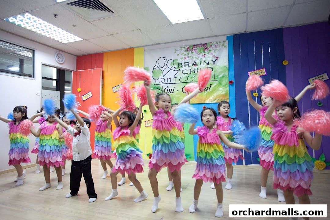 Children in colorful rainbow dresses perform a dance with pom-poms at Brainy Child Montessori.