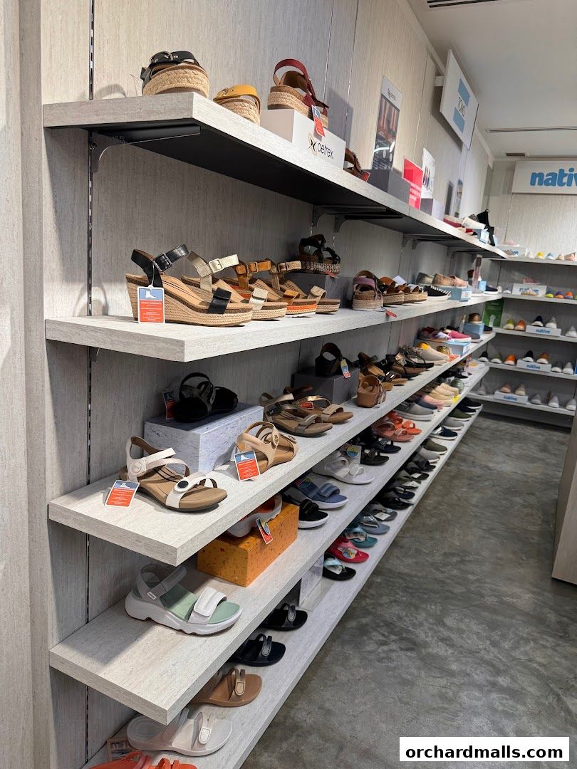 Shelves filled with various styles of sandals and shoes in a retail store.