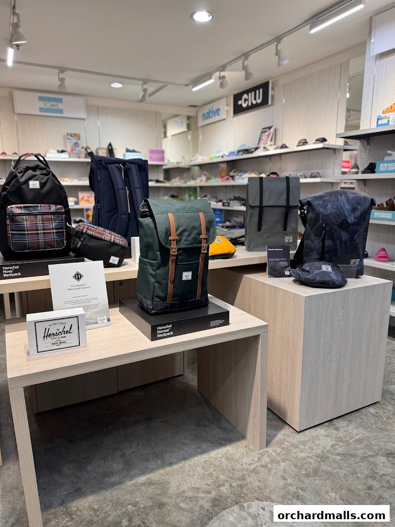 Display of various Herschel backpacks and other accessories in a retail store.