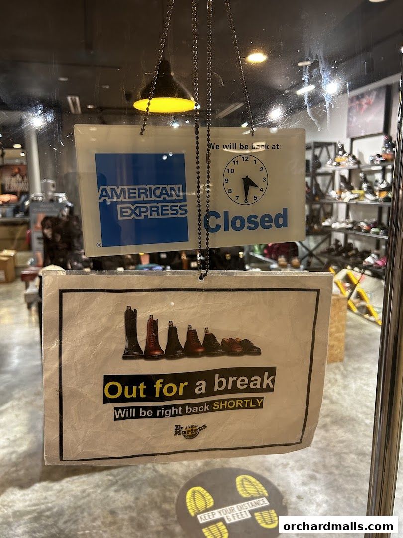 A shop door with signs indicating it's closed for a short break and accepts American Express.