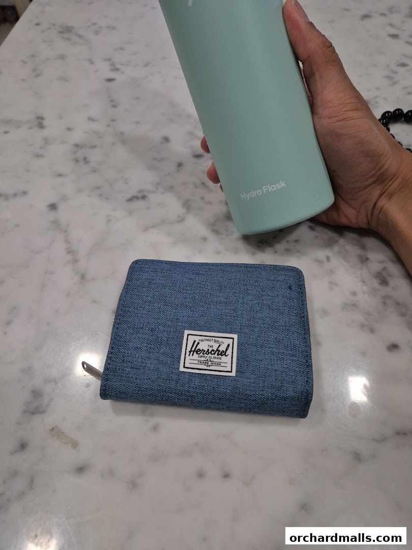 A blue Herschel wallet and a mint green Hydro Flask water bottle.