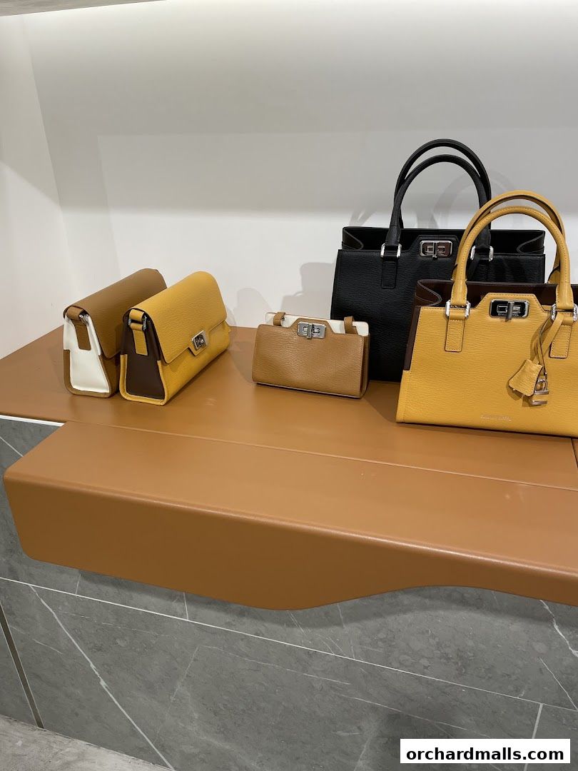 A display of elegant leather handbags in various sizes and colors on a brown shelf.