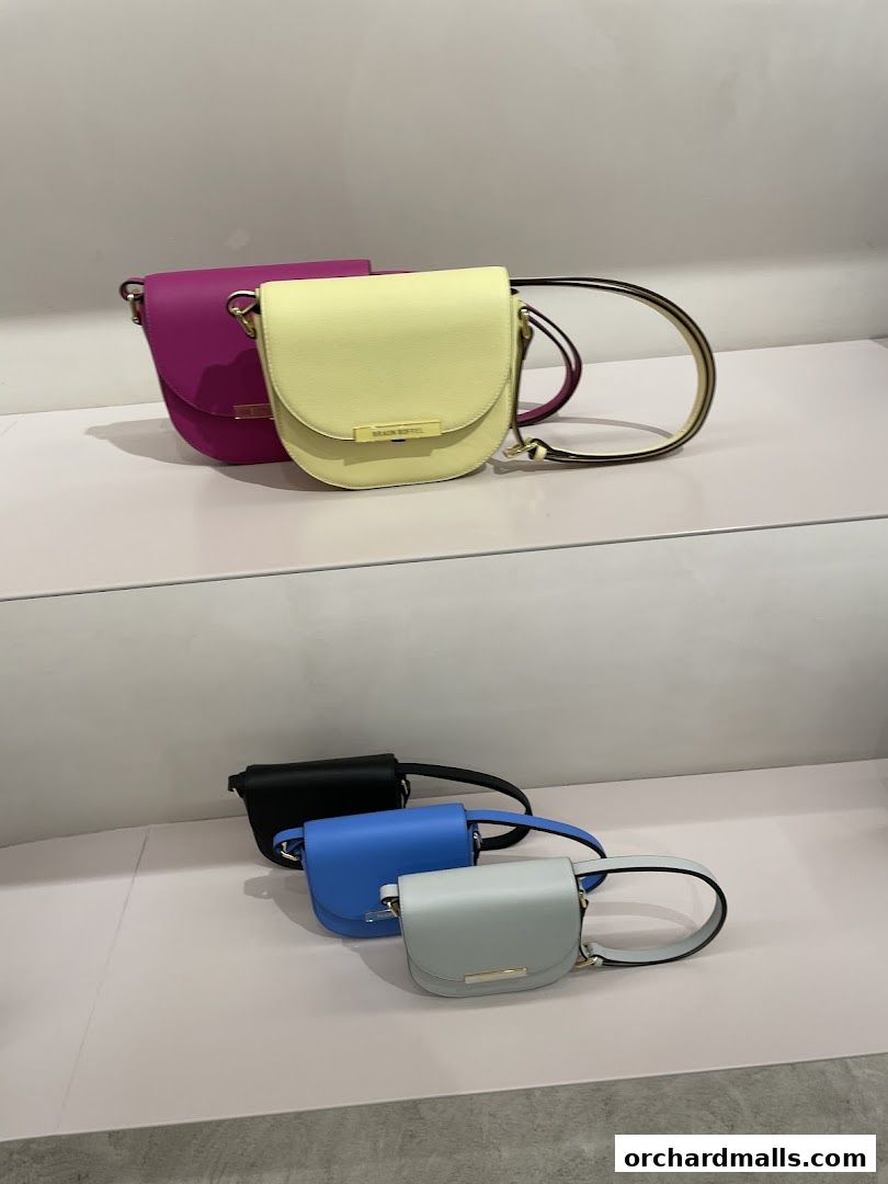 A display of colorful Braun Büffel handbags on shelves in various pastel and dark shades.
