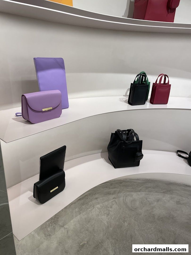 A display of various leather handbags in different colors and styles on white shelves.