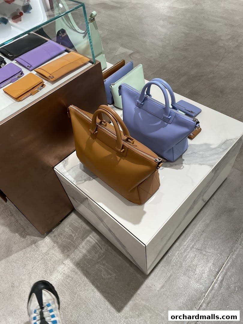 A display of stylish leather handbags and wallets in various pastel colors.