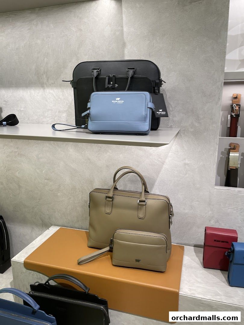 A display of various Braun Büffel leather bags, including briefcases and clutches, in different colors.