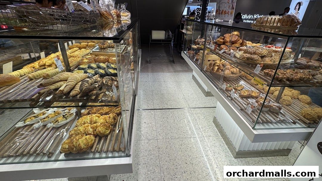 A display of various baked goods, including bread, pastries, and tarts, in glass cases.