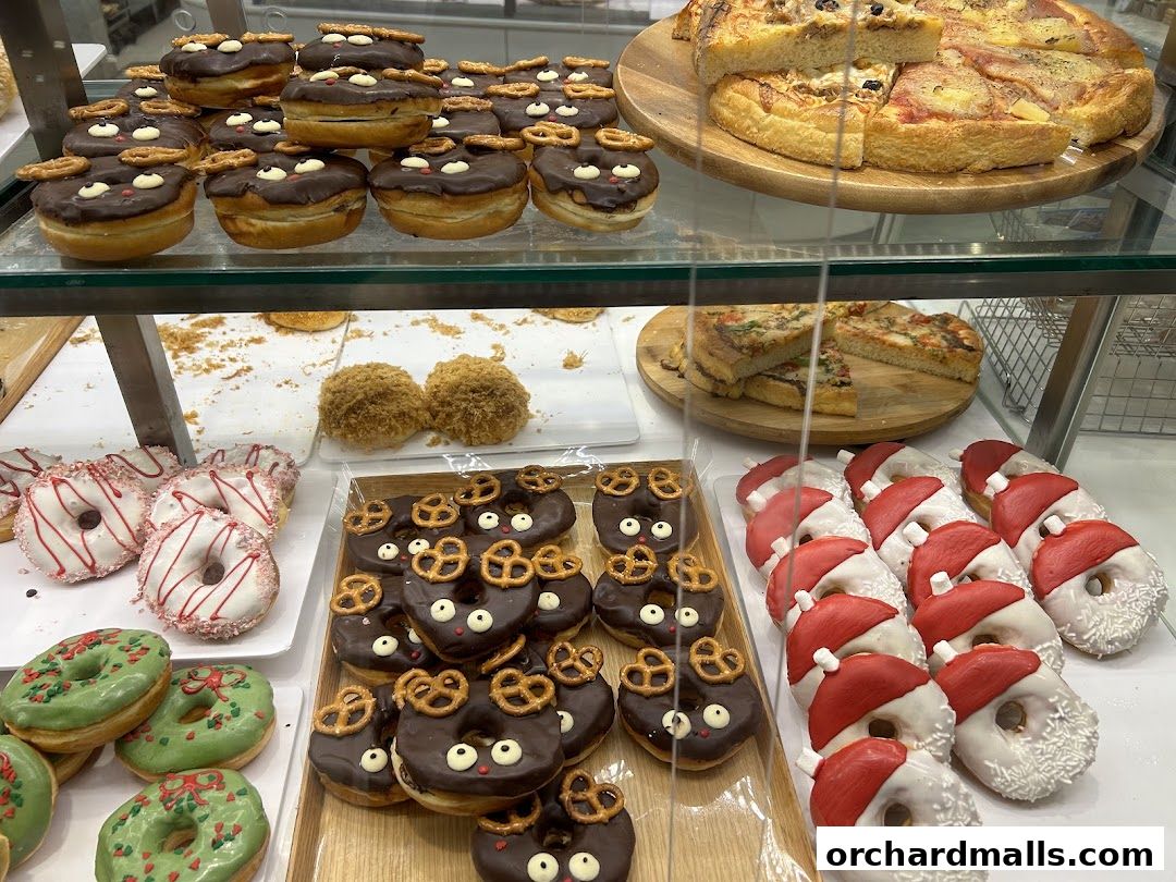A display case filled with various donuts, pizzas, and other baked goods.