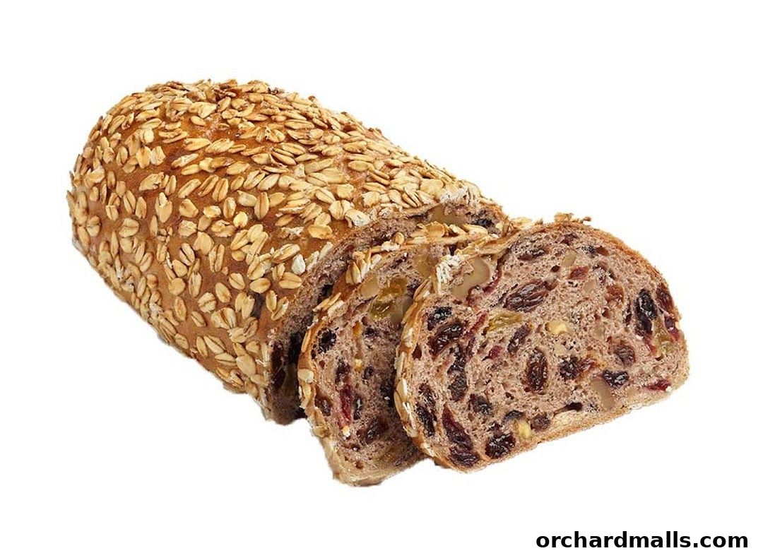 A sliced loaf of bread covered in oats with visible nuts and dried fruits inside.